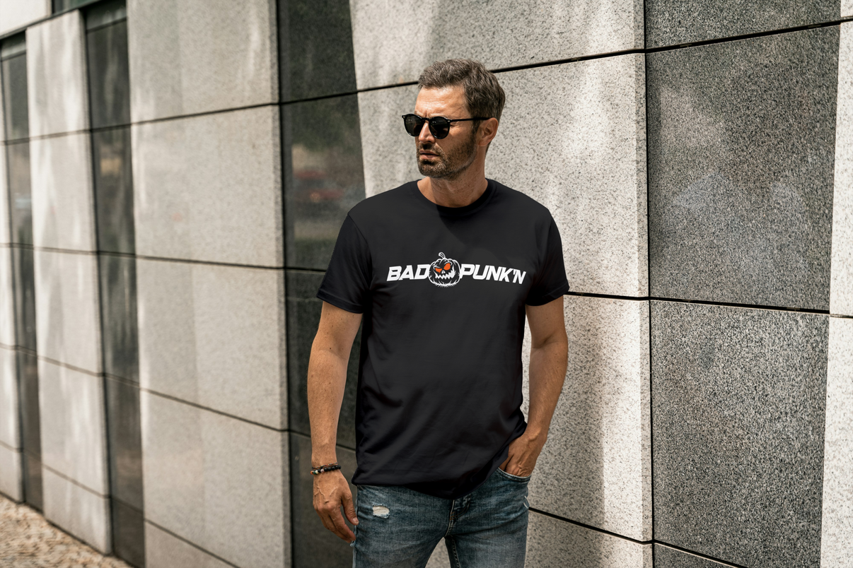 Man wearing a black t-shirt with "Bad Punk'n" design, standing against a textured wall.
