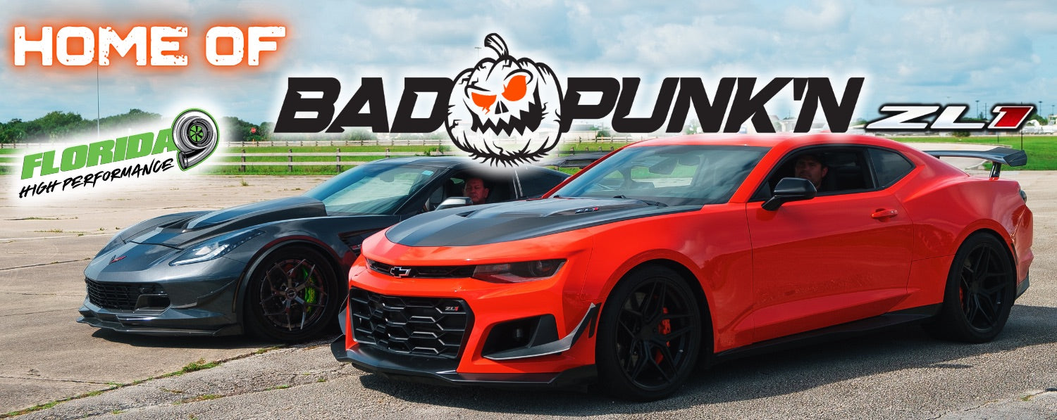 Two sports cars: A Corvette and a Camaro ZL1 nicknamed "Bad Punk'n" in a parking lot with a clear sky background.